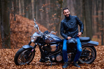 Fototapeta na wymiar Handsome biker in the forest in autumn.