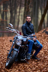 Handsome biker in the forest in autumn.