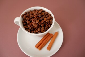 Coffee beans and cup and saucer on pink brown background. Cafe, restaurant design elements. 