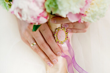 Cameo on a wedding bouquet in women's hands. Bouquet in the hands of the bride