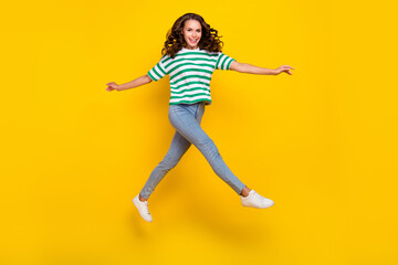 Fototapeta na wymiar Full length photo of impressed brunette young lady wear t-shirt jeans footwear isolated on yellow background
