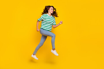 Full body photo of cute brunette millennial lady run wear t-shirt jeans shoes isolated on yellow background