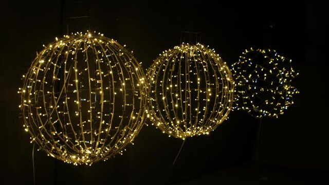 Close-up of 3 yellow gold large round LED glowing balls isolated on black background. Christmas decorative figures