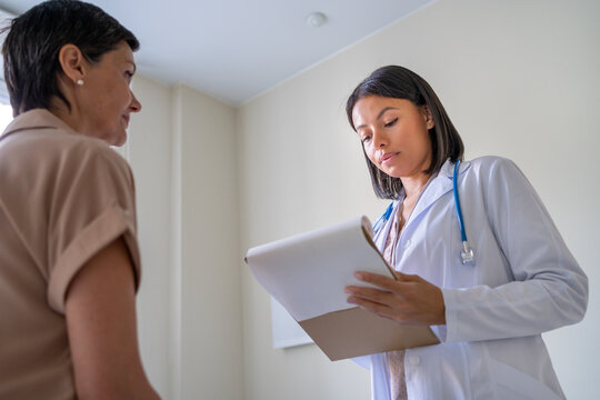Doctor attentively listening to patient complaints. Making notes on clipboard at appointment