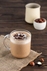 Hazelnut moсacсino coffee in a glass mug on a wooden table.