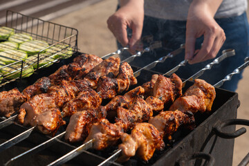 Woman preparing meat on skewers and vegetables on the grill grill in the backyard