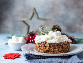 Christmas fruit cake or pudding decorated with glaze, rosemary and cranberries. Traditional winter bakery. Festive Christmas or New Year background.
