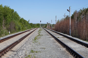 a traffic light is lit in red in the middle of two train tracks