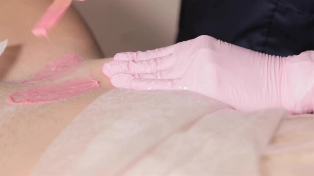 Gentle bright waxing in the treatment room. Depilation master a woman applies sugar paste to the bikini area during the epilation procedure