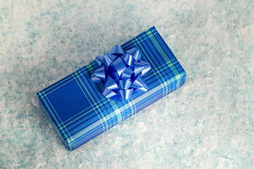 Blue gift box with a beautiful bow in the snow