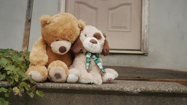 Two toys sit lonely on the threshold of an old house