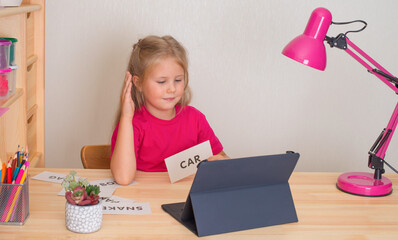 Little girl learning English online at home. Online education concept.