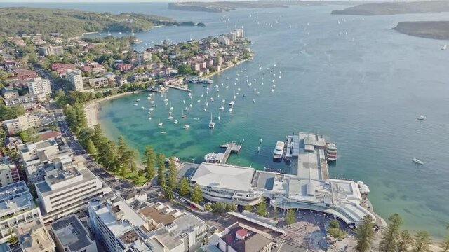 Stunning evening aerial drone 4k footage, flying over Manly Cove with ferries docked at Manly Wharf. Beautiful view of Sydney Harbour with Sydney CBD in the background. New South Wales, Australia.