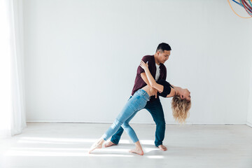 a man and a woman dance to the music of a paired dance of bachata in a white room