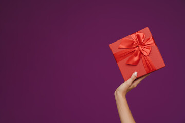 White woman's hand showing gift box at camera