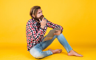 thoughtful handsome bearded guy with unshaven face and stylish hairdo wear casual clothes writing...