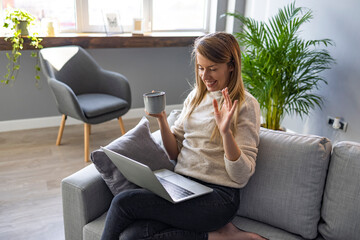 Cropped shot of an attractive young businesswoman sitting and vlogging on her laptop while enjoying a cup of coffee. Attractive young woman using her laptop to make a video call at home
