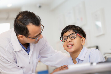 Indian child choosing eyeglasses in optics store, Boy doing eye test checking examination with...
