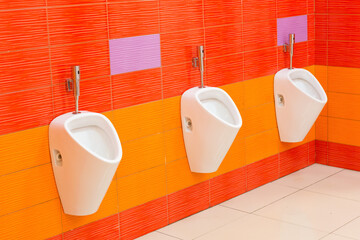 Creative men's toilet in bright orange colors in the mall.