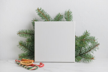Mockup poster on white table, Christmas concept. Blank wrapped canvas and Christmas decoration. Copy space for message or photo. 