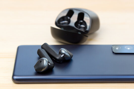 New Black Wireless Headphones On The Back Of A Blue Smartphone.