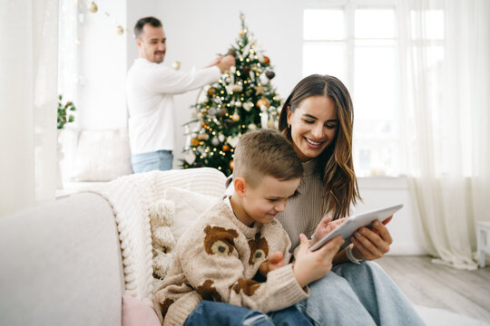 Portrait of a smiling young woman with her son using digital tablet on winter holidays - Powered by Adobe