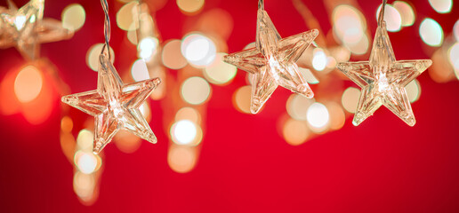 String of star shaped Christmas lights on red background. Holiday decoration