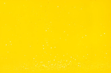 Falling shiny golden star shaped confetti on yellow background. Great backdrop for any holiday or event with copy space.