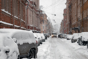 Stormy heavy snow and snow-covered cars on the street in the historical center of the city.
