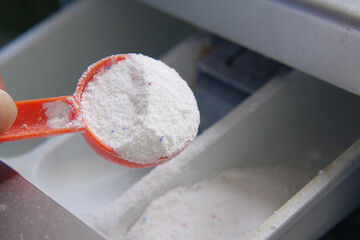 pouring Washing powder in plastic tray of washing machine 