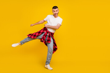 Fototapeta na wymiar Full body photo of young amazed man wear checkered shirt on waist empty space dance isolated on yellow color background