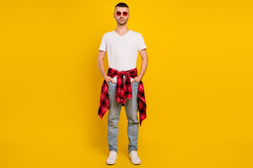 Full length photo of serious young man wear plaid shirt tied on waist sunglass isolated on yellow color background