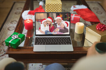 Smiling caucasian family in santa hats at christmas smiling on laptop video call screen