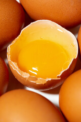 fresh chicken eggs on white background, one broken egg, vertical closeup