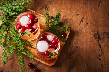 Alcoholic cocktail or non-alcoholic cocktail with vodka and cranberries with ice with fir branches on wooden background - obrazy, fototapety, plakaty