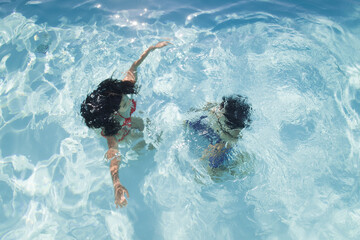 abstract portrait of girl and boy playing underwater in swimming in the pool