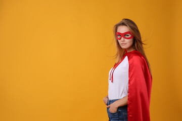 Confident woman wearing superhero cape and mask on yellow background. Space for text © New Africa