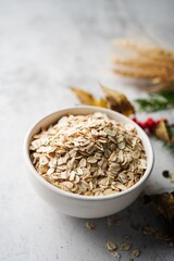 Old fashioned rolled oats in a white bowl on holiday background, selective focus