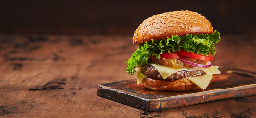 Homemade burger with beef, cheese and onion marmalade on a wooden board. Fast food concept,...
