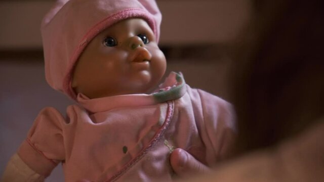 Kid playing with doll. Scary doll with pink hat and scary eyes. baby doll help by a child. horror movie