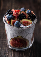 Healthy chia pudding with figs and dark berries in glass on the rustic background. Selective focus. Shallow depth of field.

