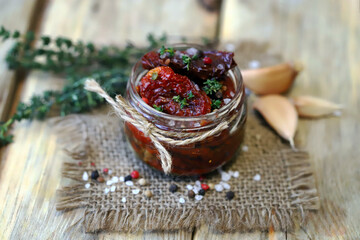 Selective focus. Sun-dried tomatoes in a jar with spices and garlic.