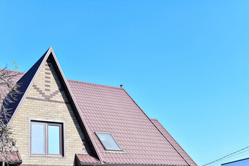 Obraz premium A house with a roof made of metal tiles against the background of an empty sky.