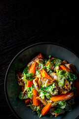 Chicken, carrot, lettice and tomato salad on black plate