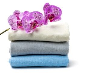 Orchid flower and towels on white isolated background. Spa, relaxation concept