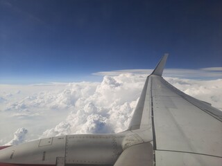Clouds and sky as seen through window of an aircraft, Airplane wing in the sky above the clouds, view from airplane window on the wing.