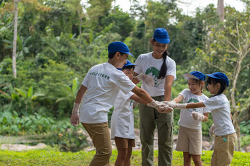 Groups of children and teachers join hands to work together to protect the environment.