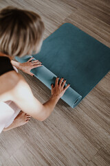 Woman rolling yoga mat in studio, closeup