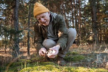 Naklejka na ściany i meble Old man sitting with mushroom on the ground in the forest