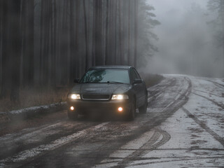 A car in a thick fog on a forest road